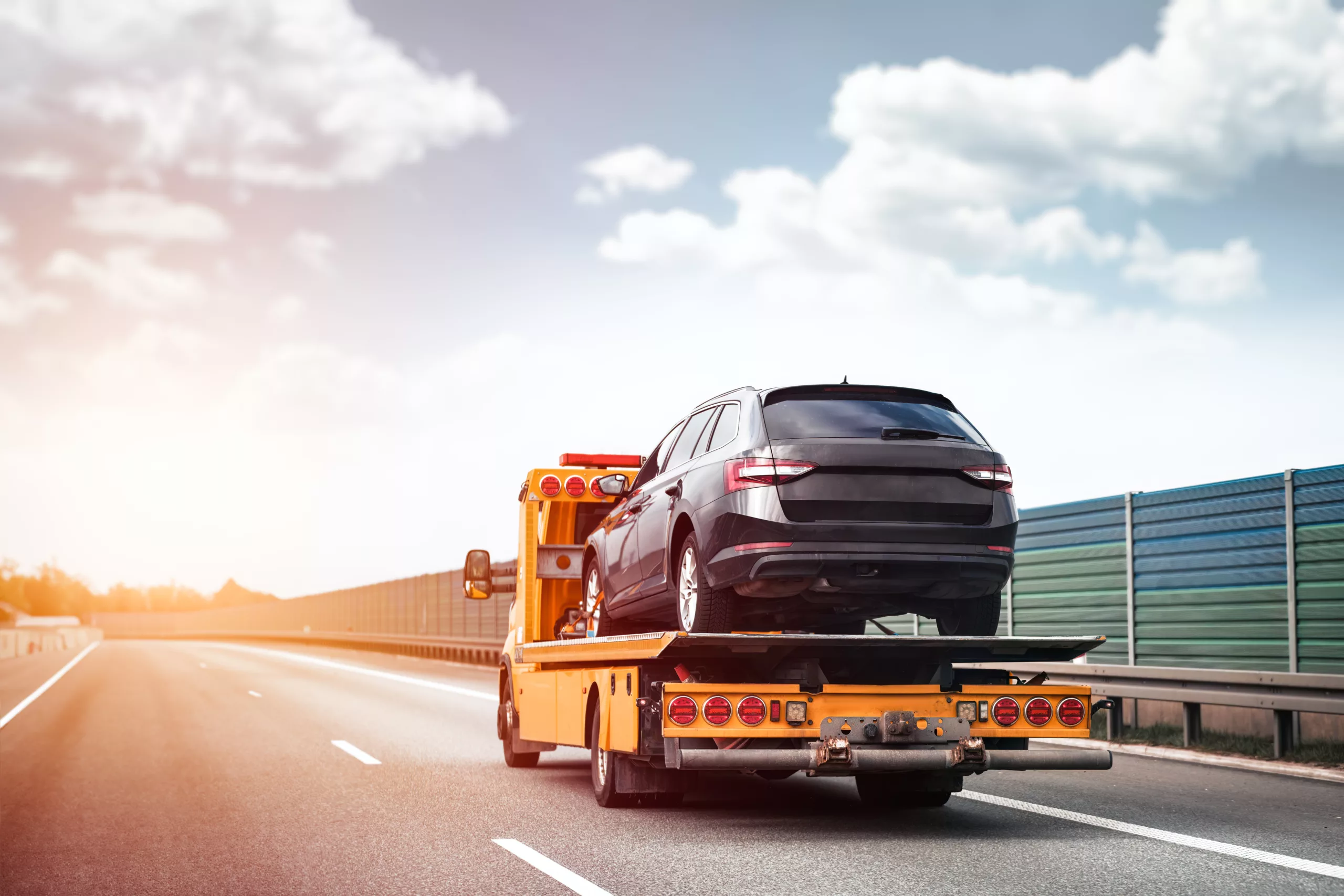 Reliable Towing and Recovery Services: 24/7 Assistance for Vehicle Breakdowns and Accidents. Emergency roadside assistance on the highway. side view of the flatbed tow truck with a damaged vehicle